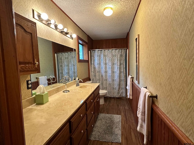 bathroom with vanity, wooden walls, hardwood / wood-style flooring, toilet, and a textured ceiling