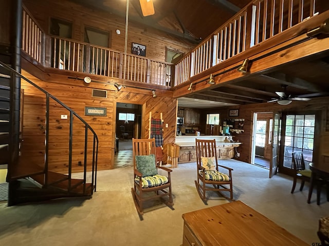 living room featuring wooden walls, ceiling fan, and high vaulted ceiling