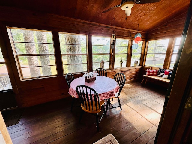 dining room featuring wooden walls, vaulted ceiling, hardwood / wood-style flooring, ceiling fan, and wood ceiling