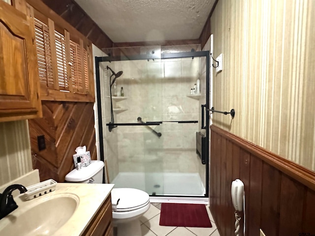 bathroom featuring tile patterned floors, wood walls, an enclosed shower, a textured ceiling, and vanity