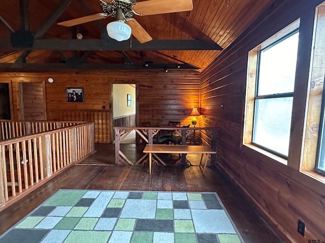 interior space with dark hardwood / wood-style flooring, ceiling fan, wooden walls, wooden ceiling, and vaulted ceiling with beams