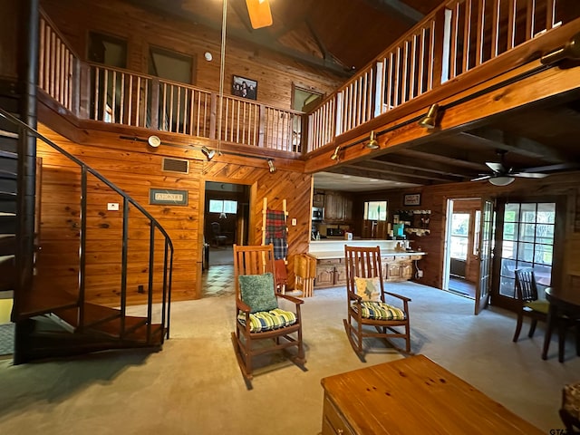 living room with wood walls, ceiling fan, and high vaulted ceiling