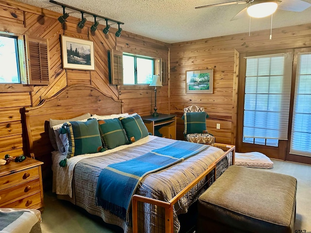 bedroom featuring a textured ceiling, ceiling fan, and wood walls