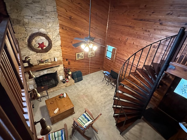 unfurnished living room featuring carpet flooring, ceiling fan, a fireplace, and wooden walls