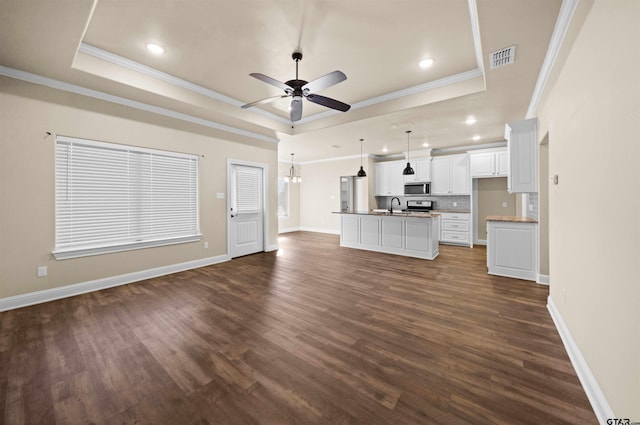 unfurnished living room featuring a raised ceiling, dark hardwood / wood-style floors, and ornamental molding