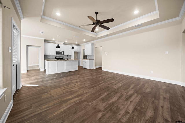 unfurnished living room featuring dark wood-type flooring, a raised ceiling, and crown molding