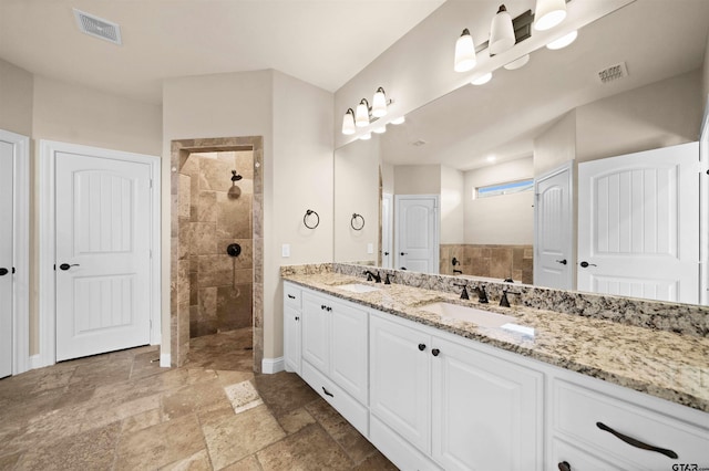 bathroom with a tile shower and vanity