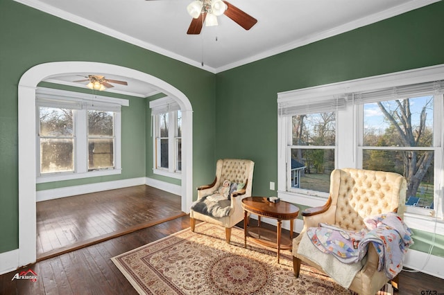 living area with hardwood / wood-style flooring, crown molding, a healthy amount of sunlight, and baseboards