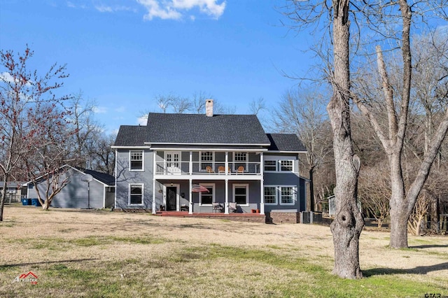 view of front of property featuring a porch, a front yard, roof with shingles, a chimney, and a balcony