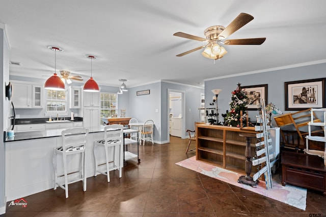 interior space with ornamental molding, a sink, glass insert cabinets, pendant lighting, and white cabinetry