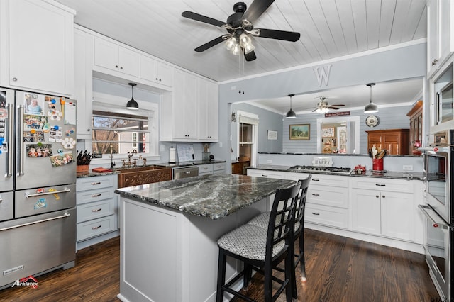 kitchen with appliances with stainless steel finishes, ornamental molding, dark wood finished floors, and white cabinetry