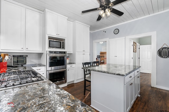 kitchen with a breakfast bar, ornamental molding, stainless steel appliances, white cabinetry, and dark wood-style flooring