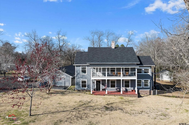 back of property with a shingled roof, a chimney, a yard, a balcony, and a deck