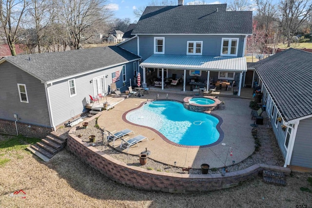 back of house featuring a patio, a shingled roof, a chimney, and a pool with connected hot tub