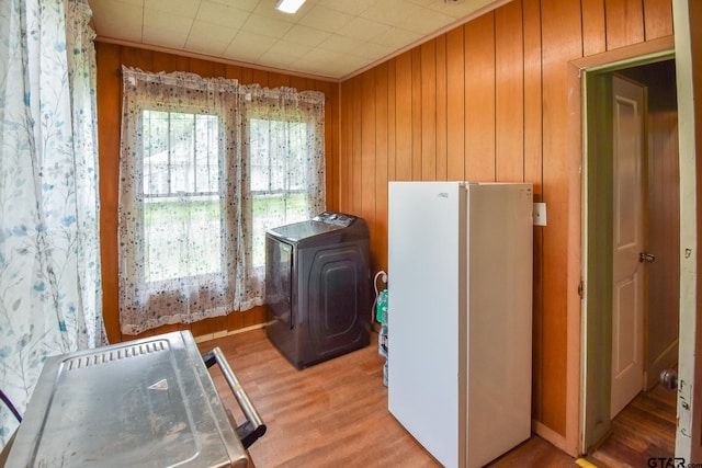 laundry area with hardwood / wood-style floors, washer / dryer, and wooden walls