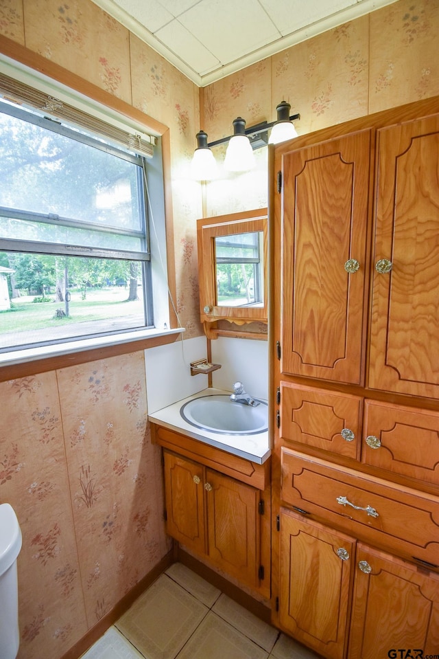 bathroom with toilet, plenty of natural light, vanity, and tile patterned floors