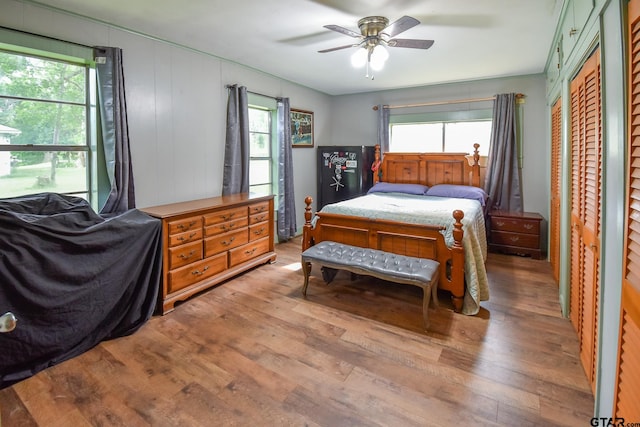 bedroom featuring hardwood / wood-style flooring, ceiling fan, and wooden walls