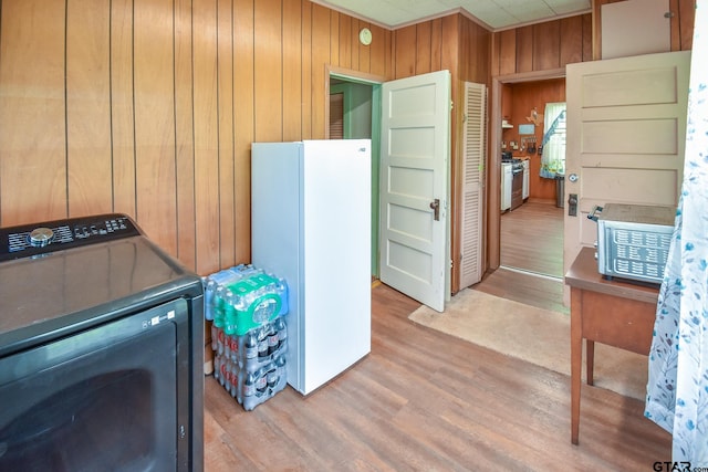 laundry room featuring wooden walls, wood-type flooring, and washer / dryer