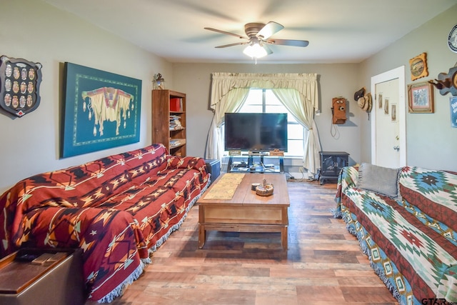 living room featuring hardwood / wood-style flooring, ceiling fan, and a wood stove