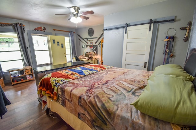 bedroom with dark hardwood / wood-style flooring, a barn door, and ceiling fan