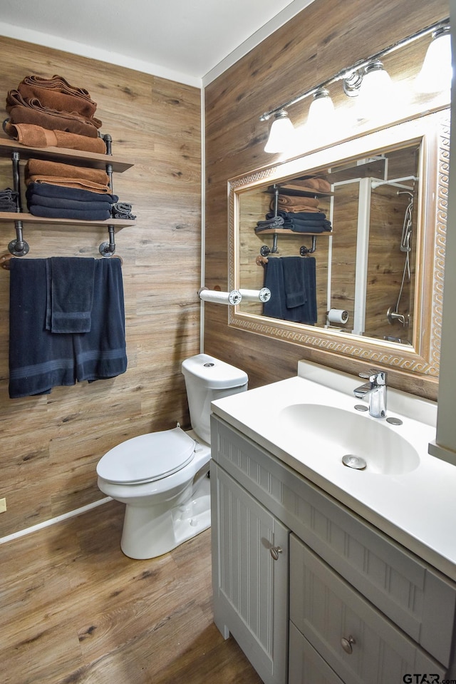 bathroom with wood walls, hardwood / wood-style flooring, vanity, and toilet