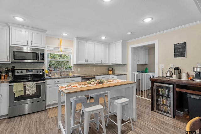 6846 Fm 346, Tyler, TX 75703 - kitchen with stainless steel appliances, wine cooler, crown molding, tasteful backsplash, and white cabinetry