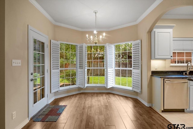 5405 Ashbury Ct, Tyler, TX 75703 - unfurnished dining area with a chandelier, light wood-type flooring, ornamental molding, and arched walkways