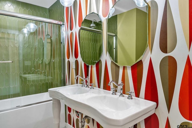 bathroom featuring double sink and combined bath / shower with glass door