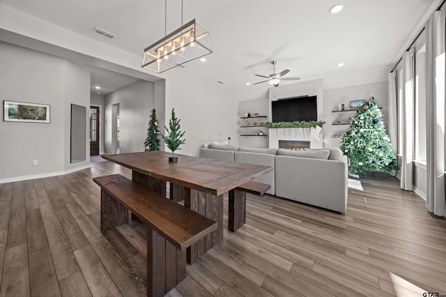 dining room with hardwood / wood-style flooring and ceiling fan with notable chandelier