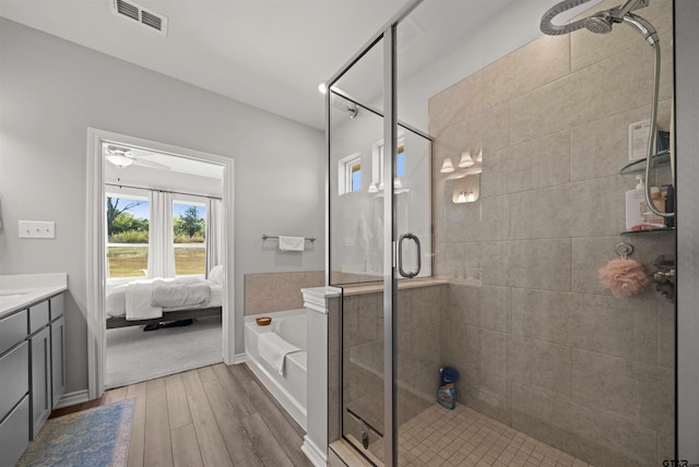 bathroom with wood-type flooring, vanity, and independent shower and bath