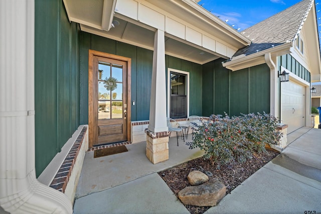 view of exterior entry featuring a porch and a garage