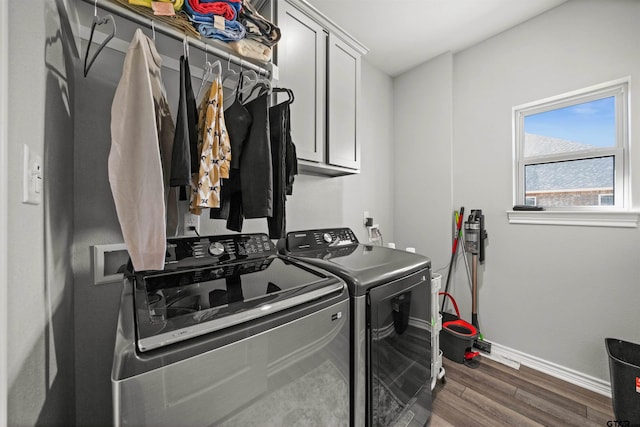 clothes washing area with cabinets, washer and dryer, and dark wood-type flooring