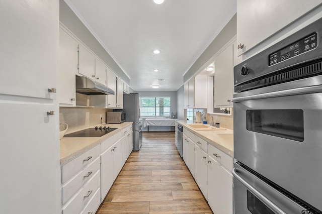 7411 Hollyoak Dr, Tyler, TX 75703 - kitchen with under cabinet range hood, stainless steel appliances, white cabinetry, tasteful backsplash, and recessed lighting