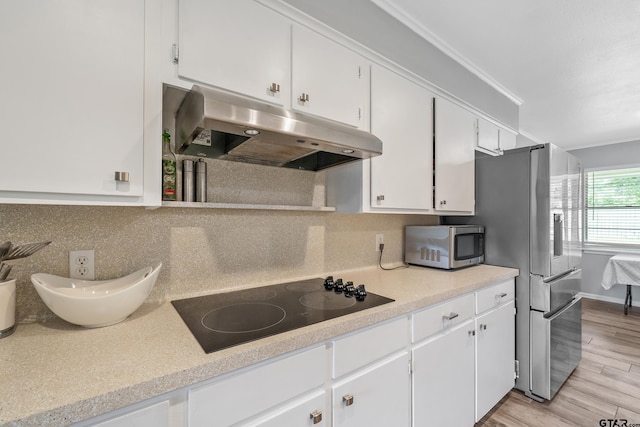 7411 Hollyoak Dr, Tyler, TX 75703 - kitchen with under cabinet range hood, black electric cooktop, stainless steel microwave, and white cabinetry