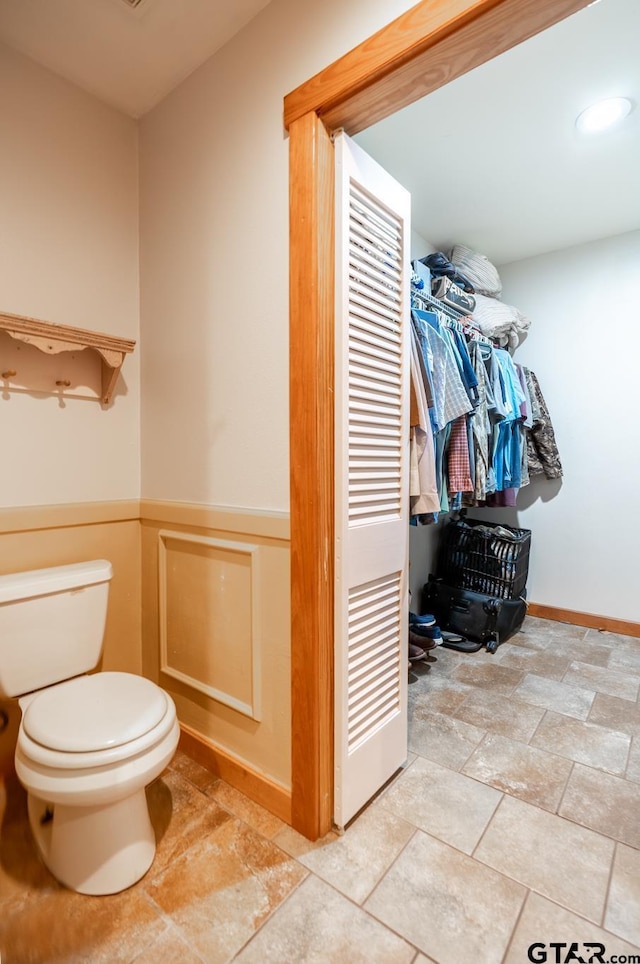 5646 Fm 346, Tyler, TX 75703 - bathroom with stone finish floor, a wainscoted wall, a closet, and toilet