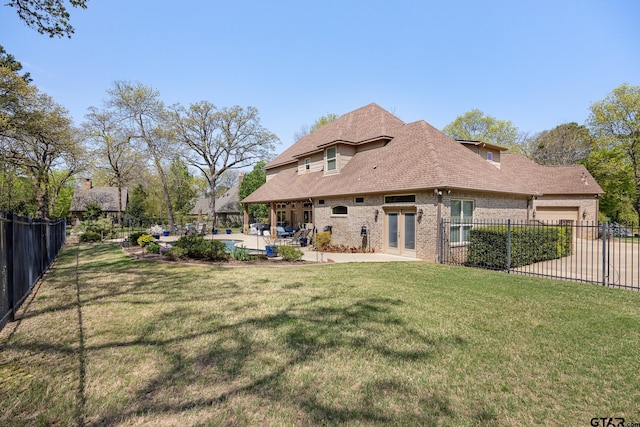 5875 Stonegate Trl, Tyler, TX 75703 - back of property featuring brick siding, an attached garage, a patio area, and roof with shingles