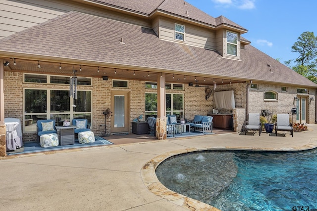 5875 Stonegate Trl, Tyler, TX 75703 - rear view of property featuring roof with shingles, a patio, an outdoor living space, an outdoor pool, and brick siding