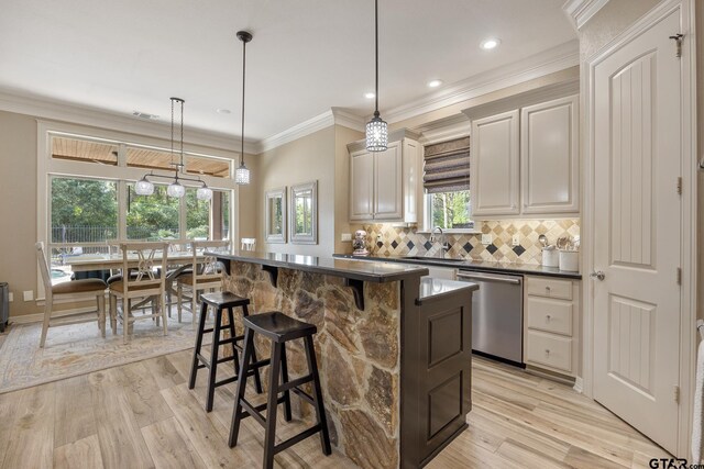 5875 Stonegate Trl, Tyler, TX 75703 - kitchen featuring dishwasher, a sink, dark countertops, light wood-style floors, and a kitchen bar