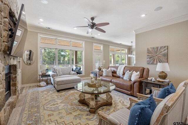 5875 Stonegate Trl, Tyler, TX 75703 - living room with a stone fireplace, crown molding, a ceiling fan, recessed lighting, and wood finished floors