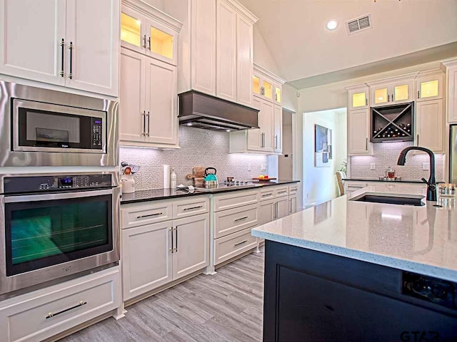 kitchen with dark stone counters, white cabinetry, sink, and stainless steel appliances