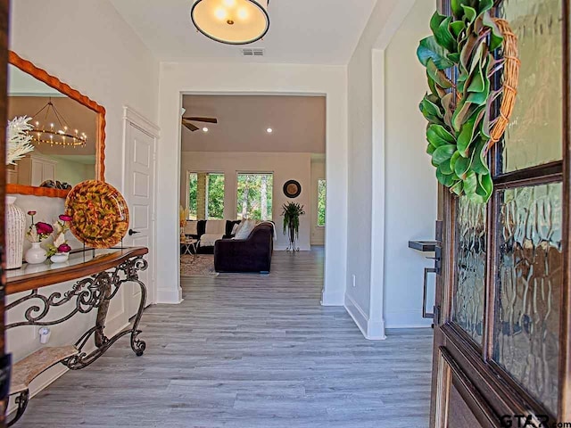 corridor with hardwood / wood-style flooring and a notable chandelier