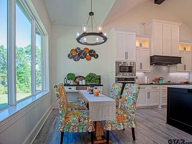 dining room featuring light hardwood / wood-style floors, a chandelier, and vaulted ceiling