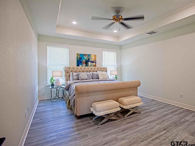 bedroom featuring ceiling fan, multiple windows, dark hardwood / wood-style floors, and a raised ceiling