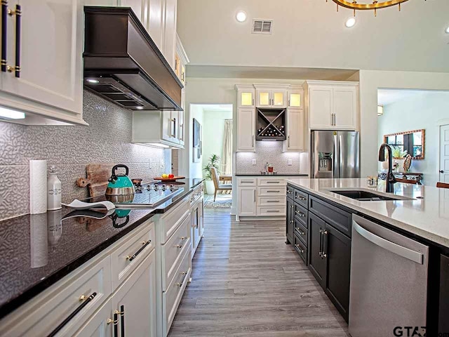 kitchen featuring stainless steel appliances, light wood-type flooring, white cabinetry, custom range hood, and sink