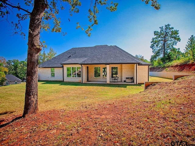 rear view of property featuring a lawn and a patio area