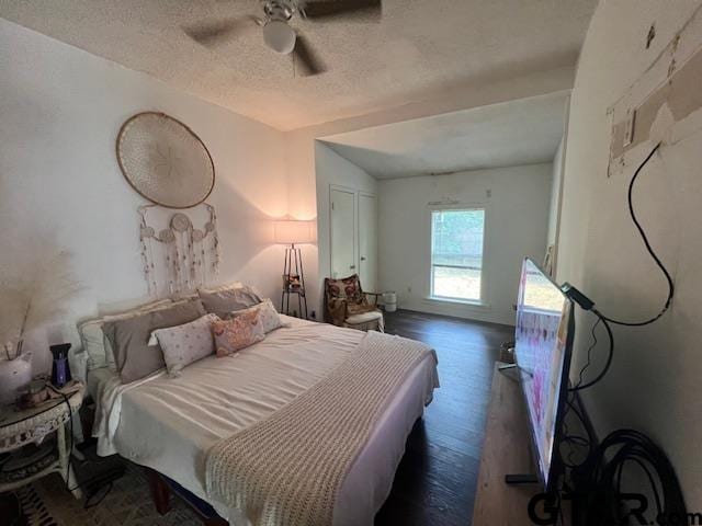 bedroom featuring dark wood-type flooring, a textured ceiling, vaulted ceiling, and ceiling fan