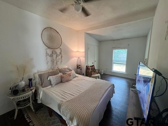 bedroom featuring ceiling fan, dark hardwood / wood-style floors, and a textured ceiling