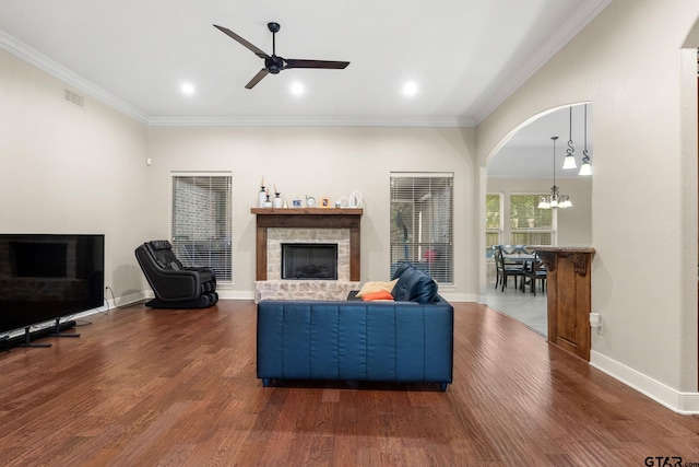 1516 Chaparrel Run, Tyler, TX 75703 - living area featuring a stone fireplace, dark wood finished floors, a chandelier, a ceiling fan, and ornamental molding