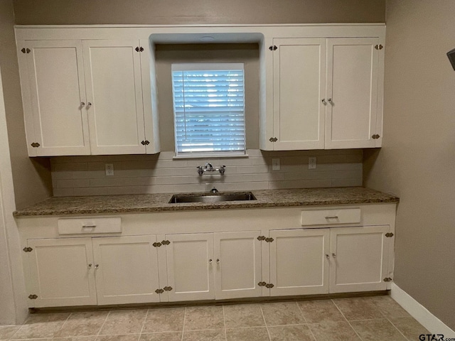 kitchen with stone counters, sink, light tile patterned flooring, decorative backsplash, and white cabinets