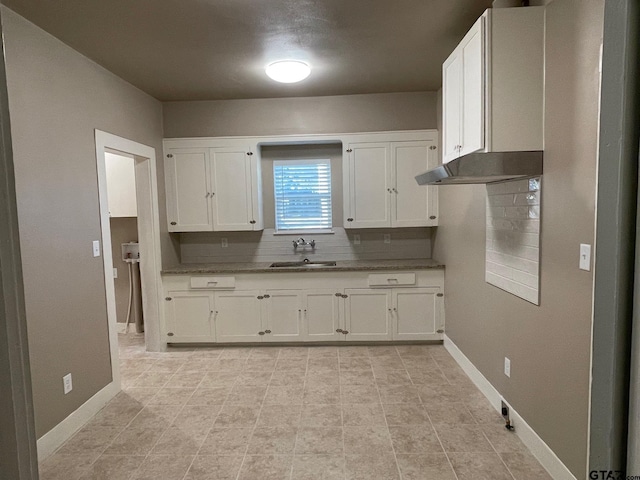 kitchen featuring tasteful backsplash, sink, white cabinets, and light tile patterned flooring